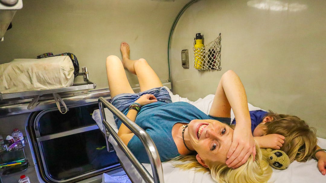 mom and son trying to sleep on a sleeper train while backpacking as a family