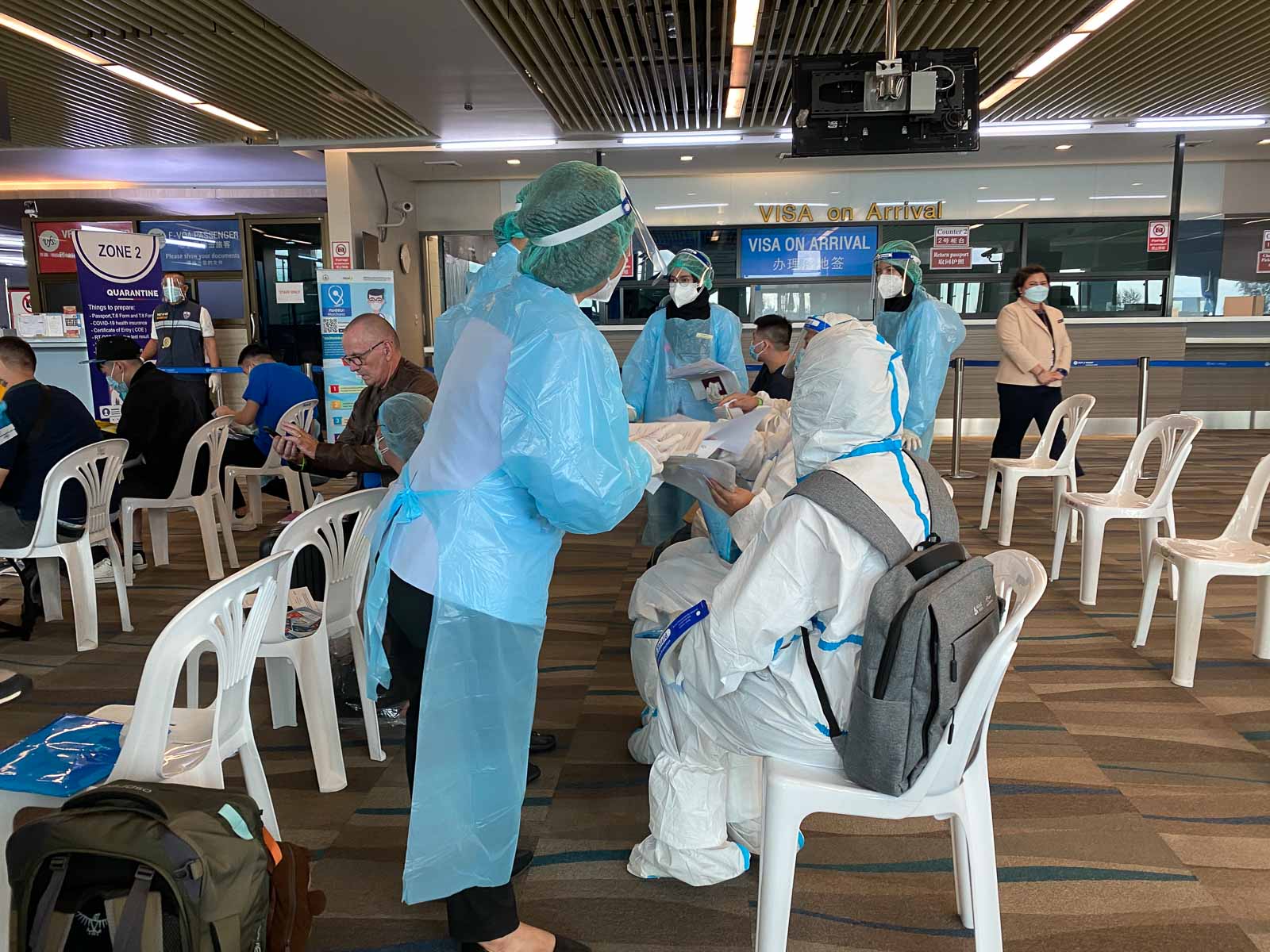 woman in a blue hazmat suit performing a covid test at an airport