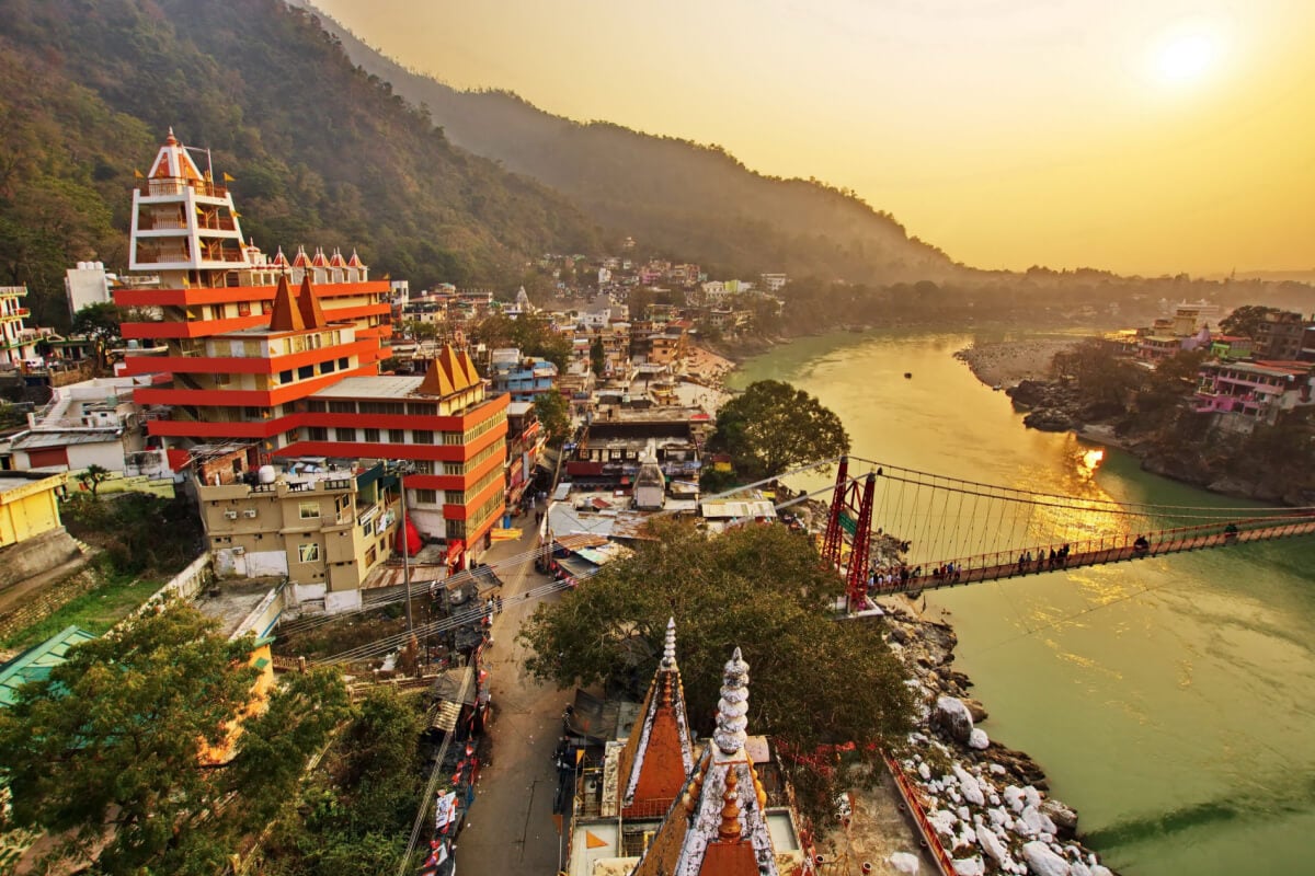 Rishikesh India at sunset. View is of the famous Lakshman Jhula bridge, the river, the hills and the city.