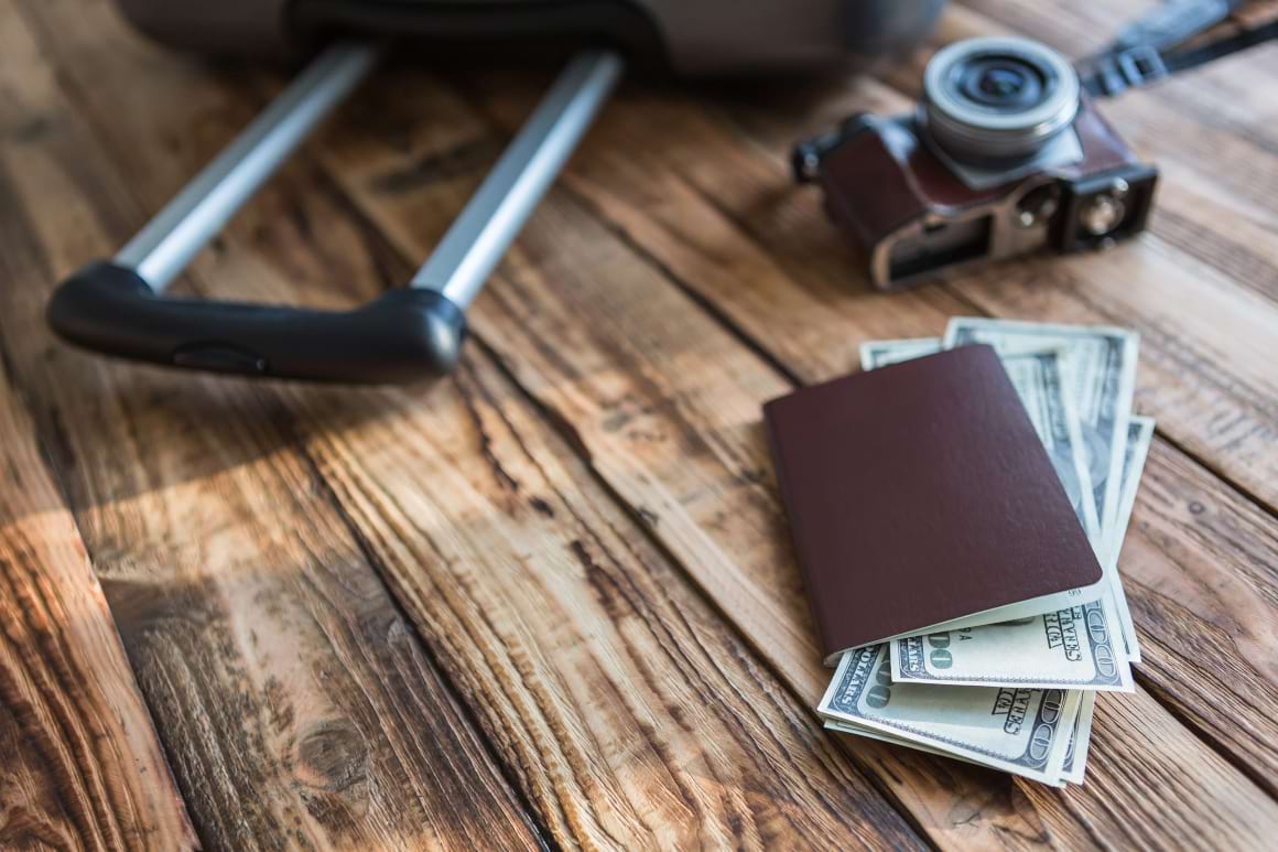 passport and camera with us dollars on wood table