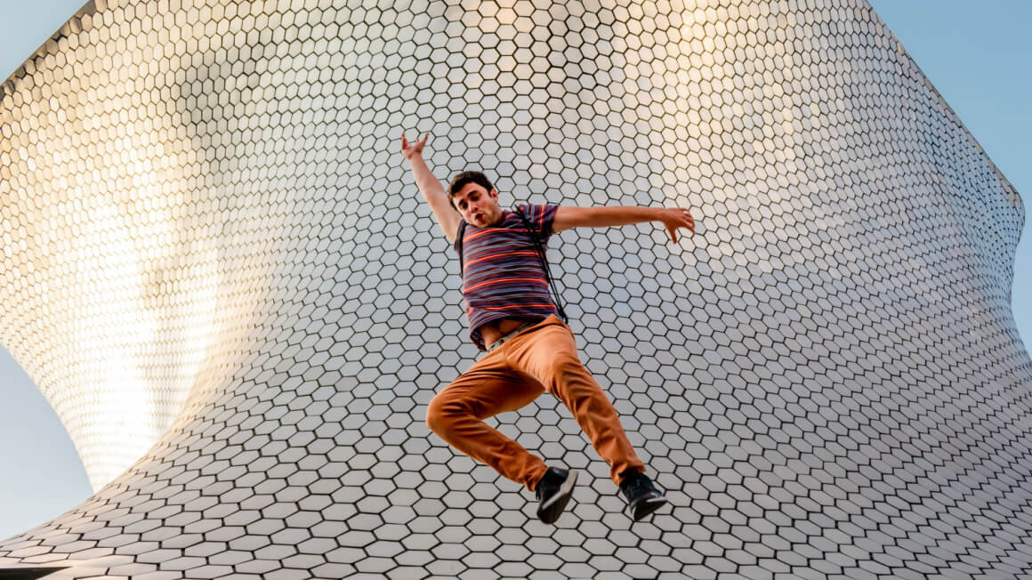 An American tourist jumping in front of some cool architecture.