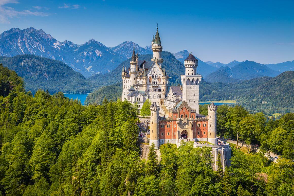 Neuschwanstein Castle standing tall in the middle of a lush forest in Munich