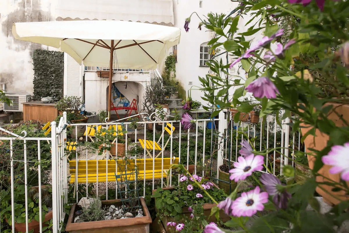 Patio full of flowers with a table and chairs