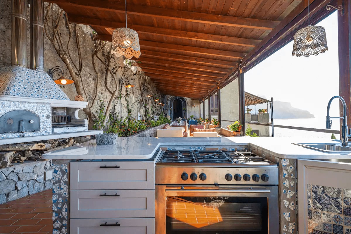 Luxurious outdoor kitchen, seating area and pizza oven with view over the ocean and cliffs