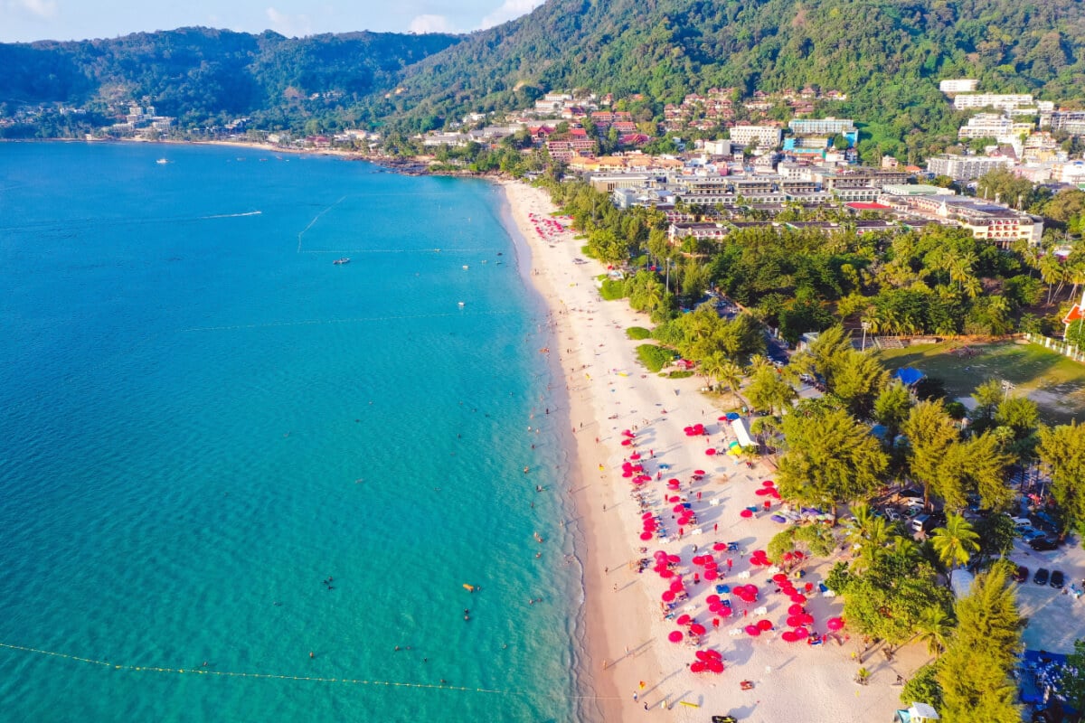 A landscape view of Phuket coastline with its lush greenery, white sand beach and turquoise water.