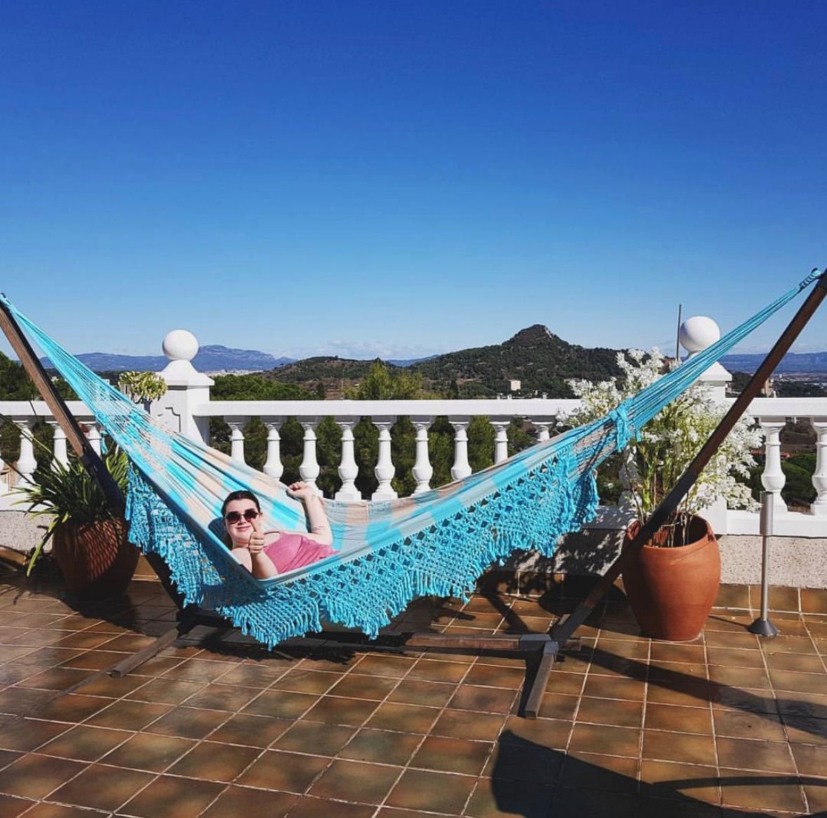 person swinging in a bright blue hammock on a sunny rooftop in barcelona spain