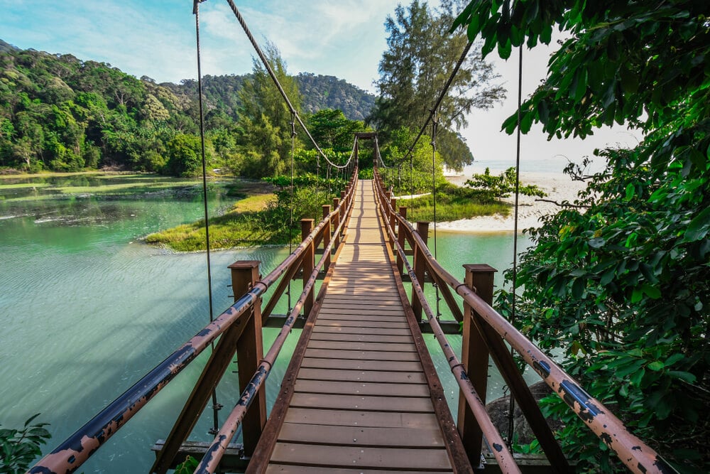 wooden bridge going over turquoise water in penang national park one of the best places to visit in penang