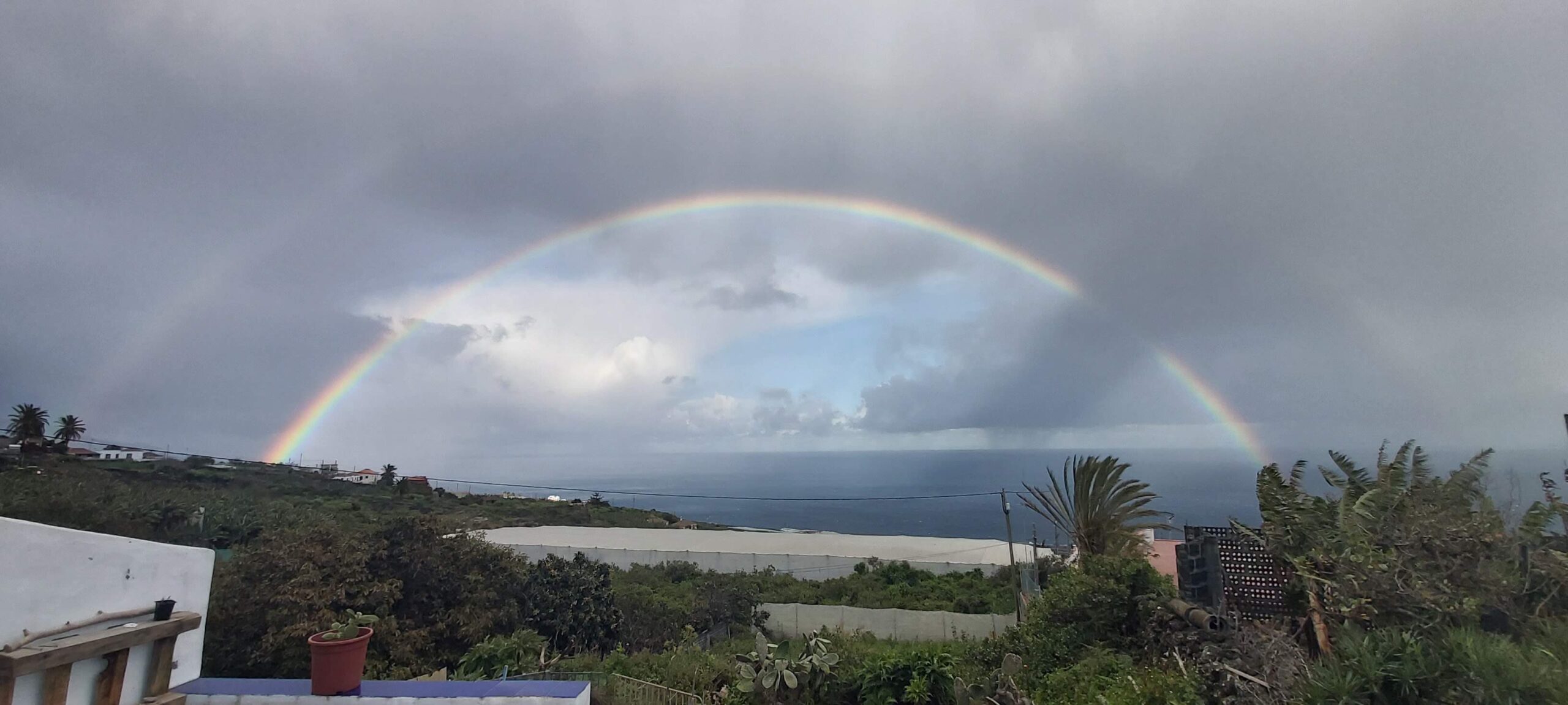 a double rainbow lighting up a stormy sky in the canary islands