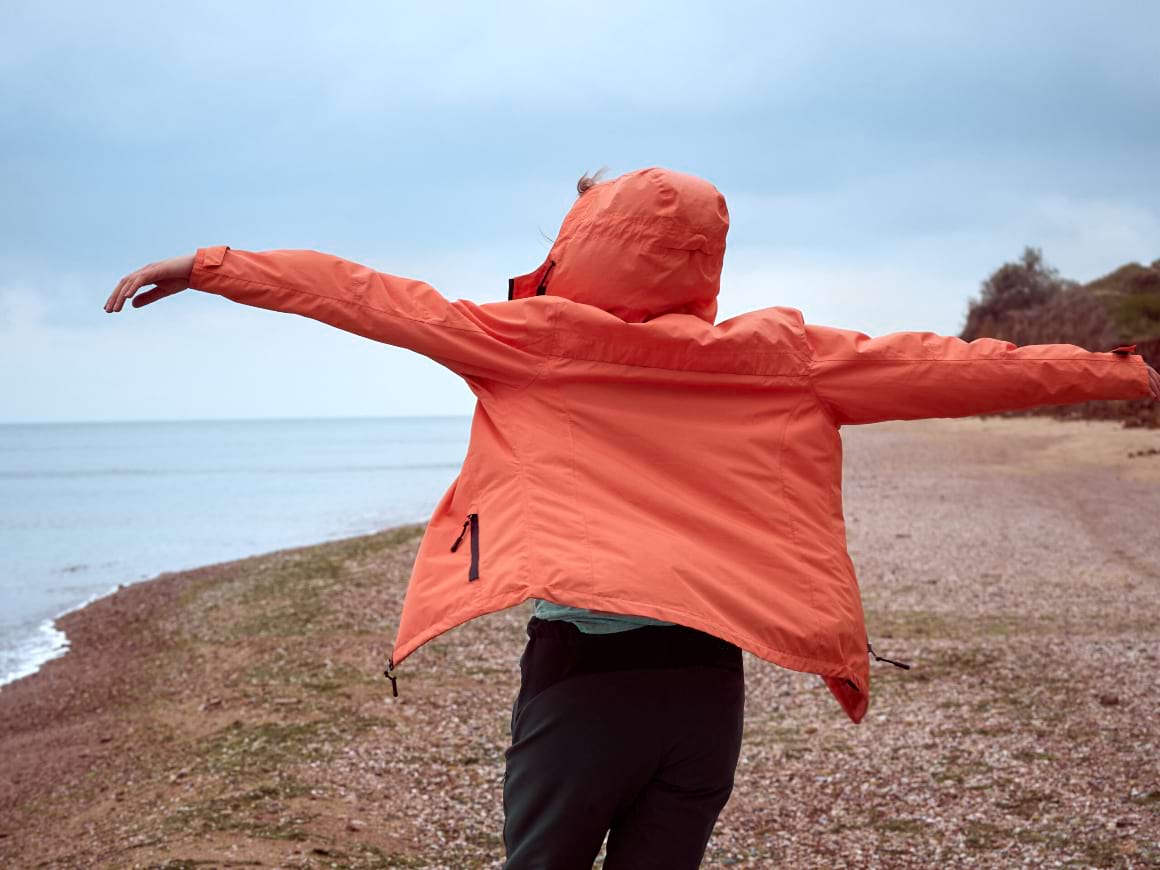 girl in a coral raincoat on the seashore