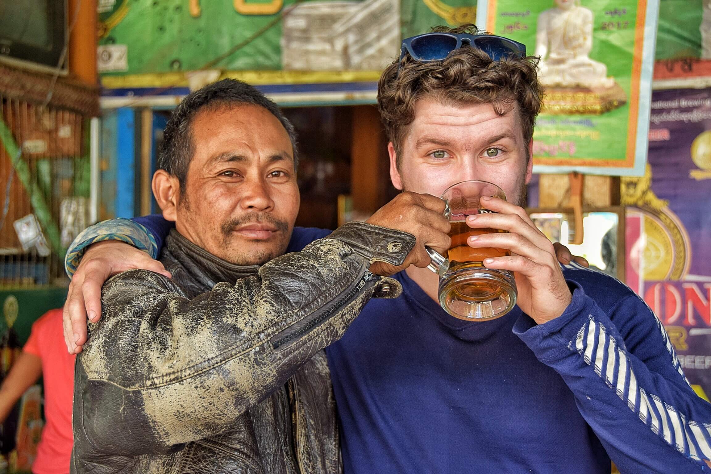backpacker drinking beer with locals in myanmar