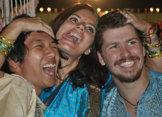 three smiling people at a wedding in india