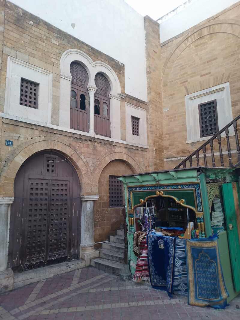 Traditional architecture of Al Zaytouna Mosque  with an old green kiosk selling prayer mats in Tunis Medina  