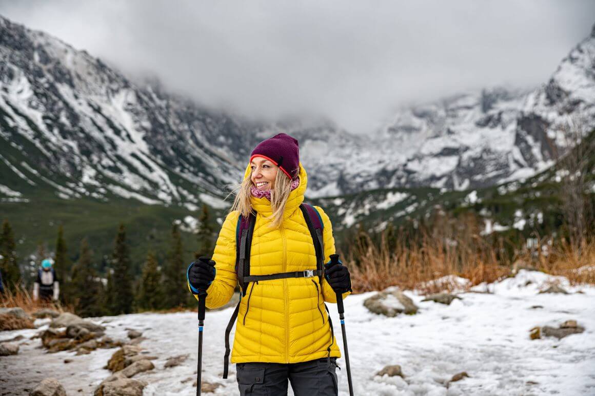 woman in down jacket hiking on a snowy mountain