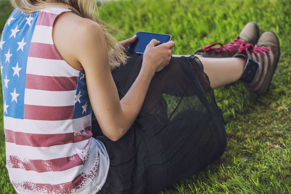 woman against green lawn with phone