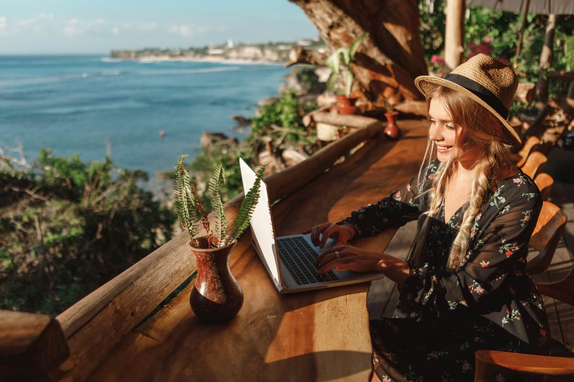 woman using laptop in outdoor cafe terrace with sea view
