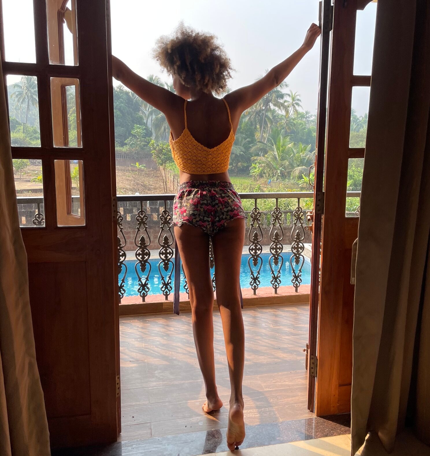 girl standing overlooking a balcony with a pool underneath whuile staying in goa