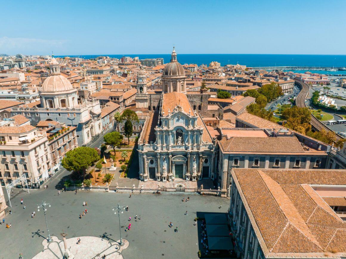 Elephant Statue fountain, Cathedral of Santa Agatha, and walking people on Piazza del Duomo square in Catania historical city centre of Sicily