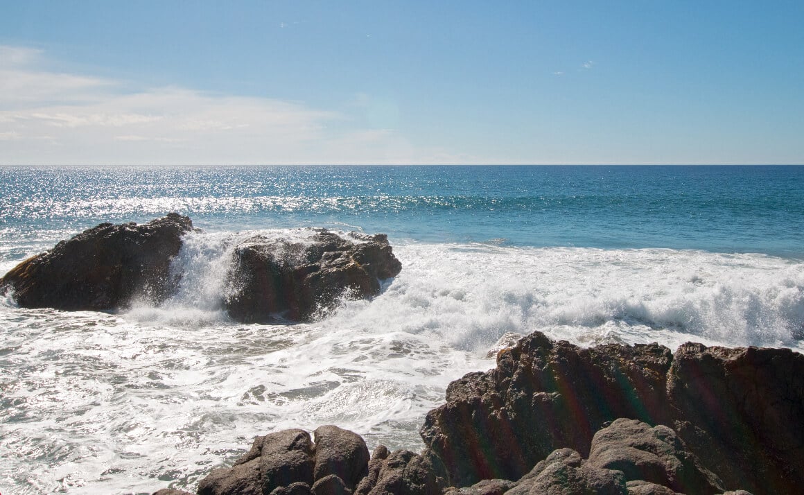 Waves crashing against rugged rock formations in Cerritos Beach, Cabo San Lucas