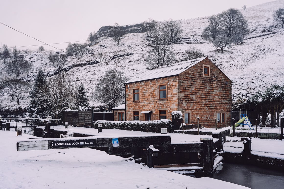 Brick house in front of a canal hills covered in snow