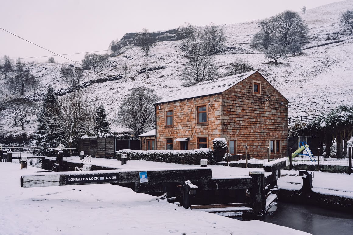 Brick house in front of a canal lock in the hills covered in snow