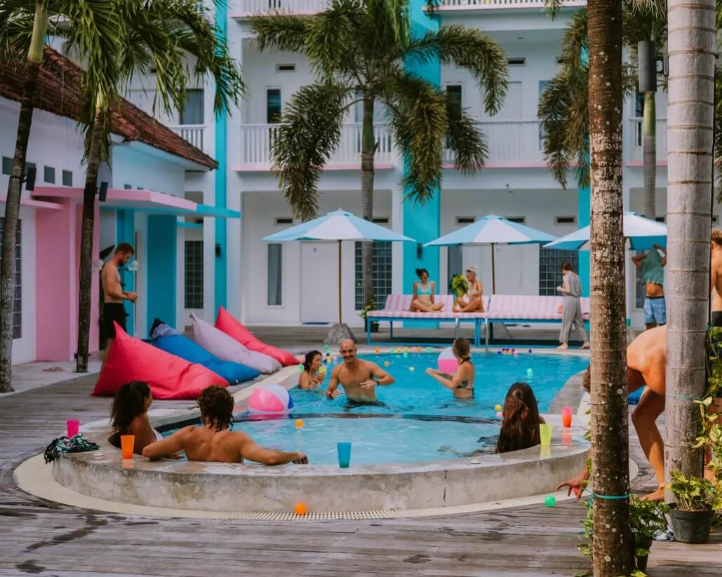 Mad Monkey Lombok outdoor pool with people playing in it under palm trees.