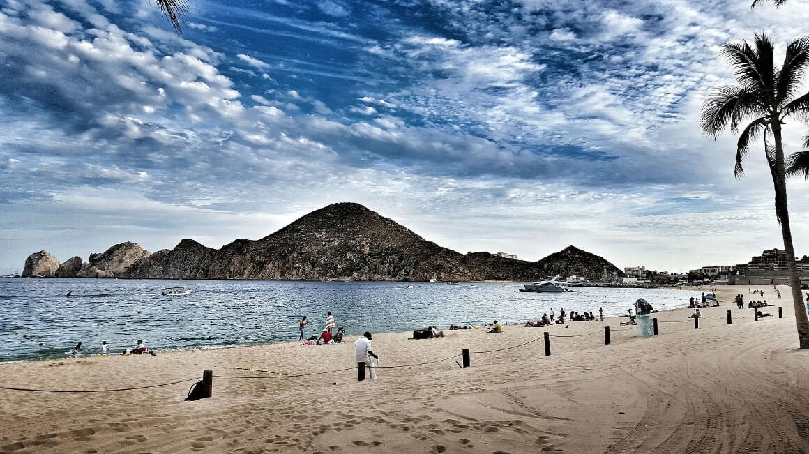 A landscape view of Medano Beach where mountains meet the ocean, with people enjoying the sandy shores.