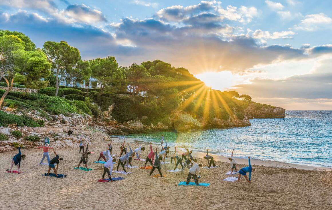 A group of people playing yoga by the beach in Palma, Mallorca