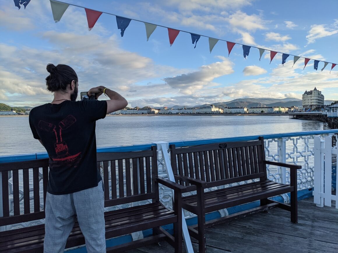 man taking a photo on Llandudno pier at dusk