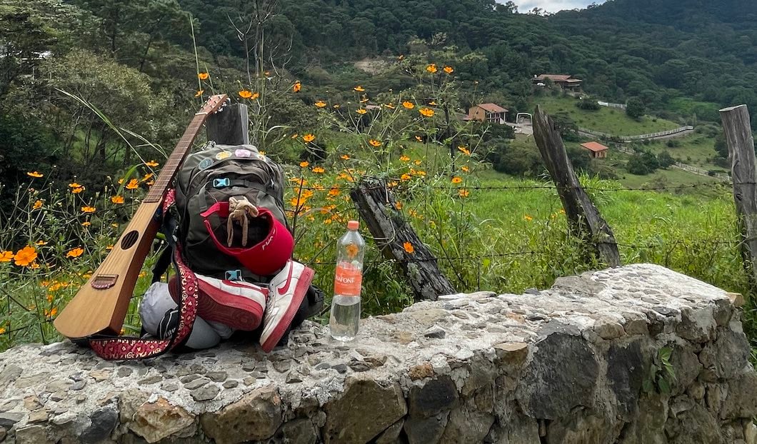 Backpack and guitar on sits on side of road while hitchhiking in Mexico.