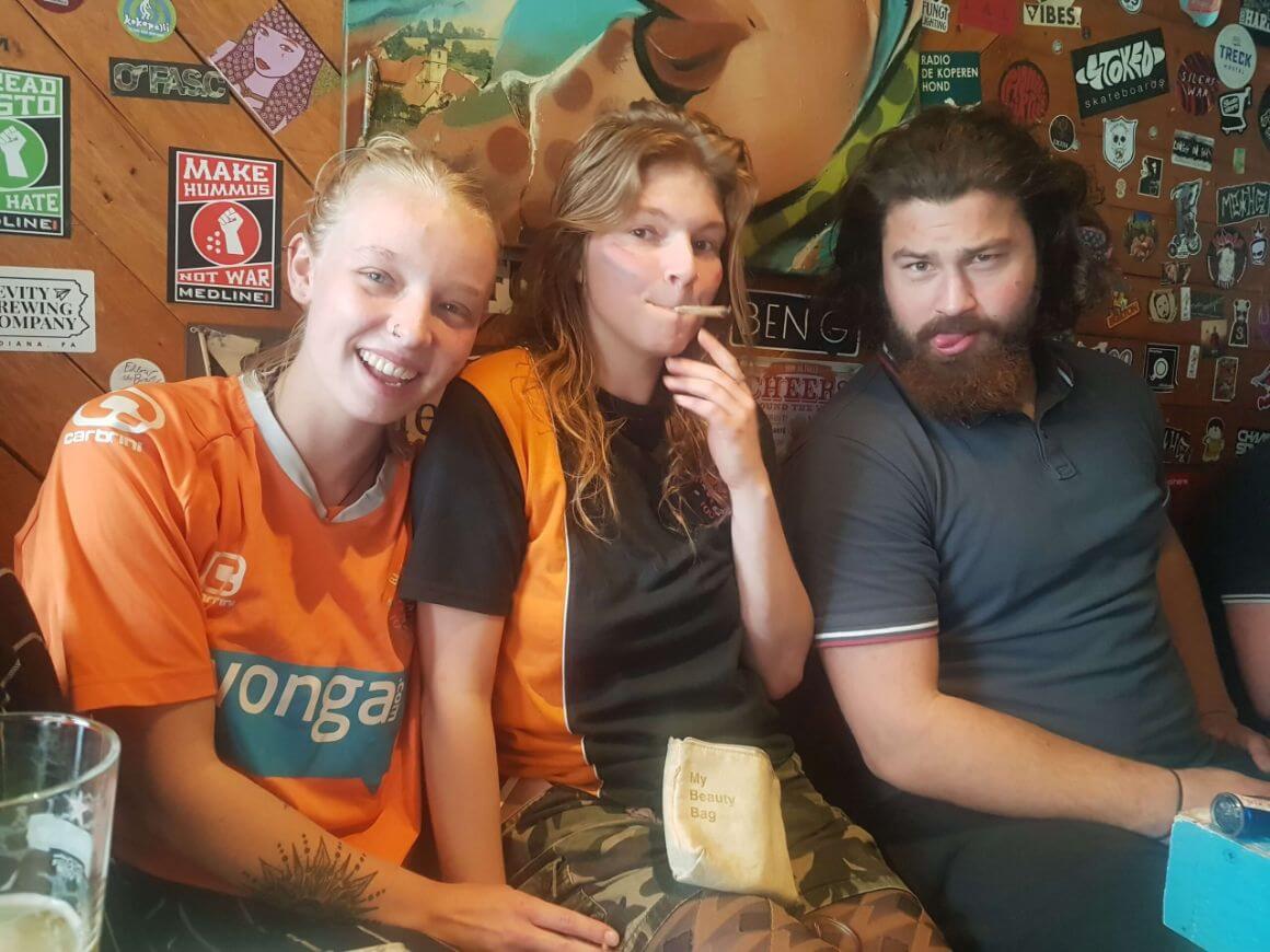 Laura and two other people smiling in a hostel in The Netherlands on King's Day