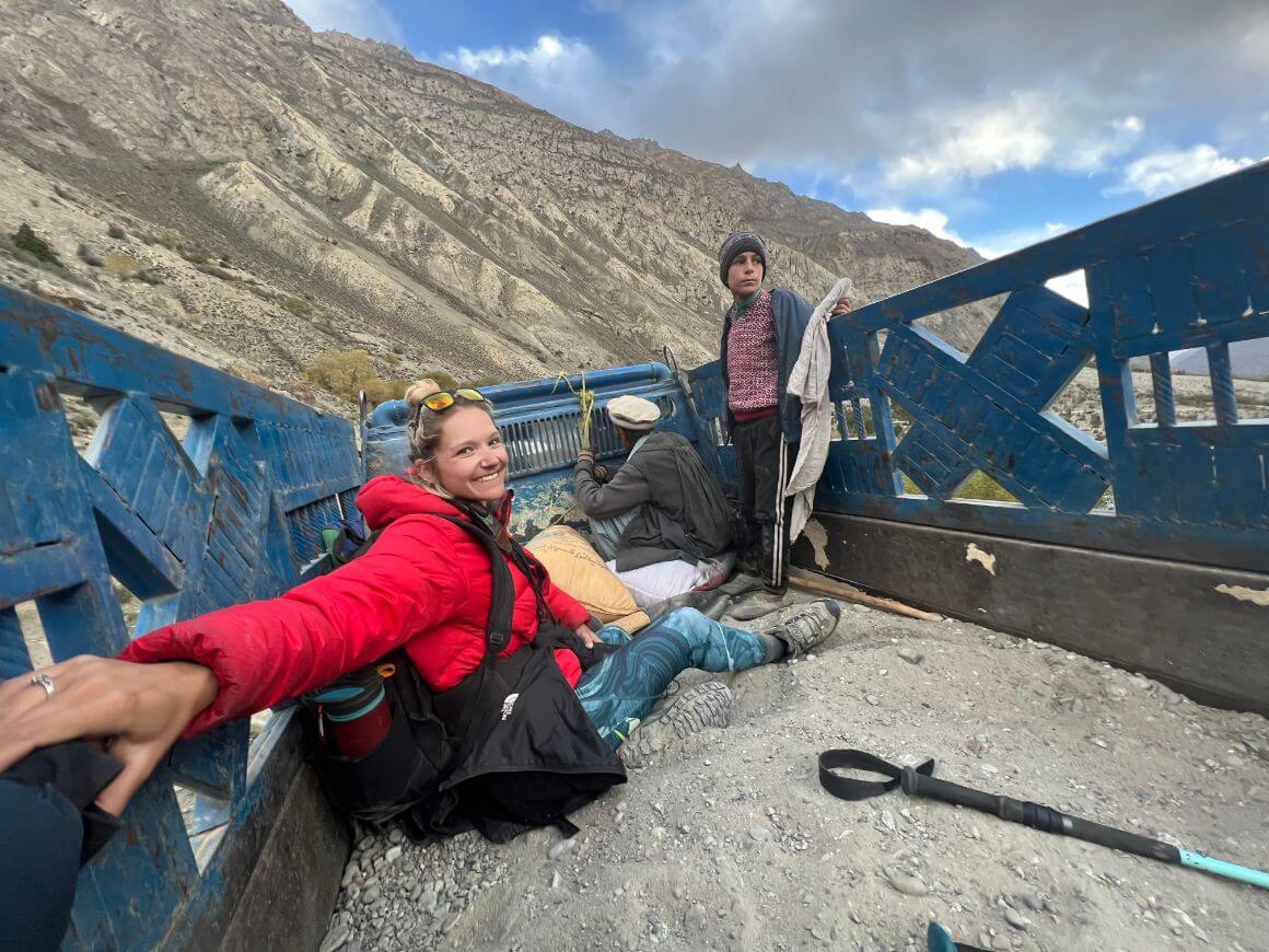 a girl hitchhiking in a blue pickup truck while overland traveling in the mountains of pakistan