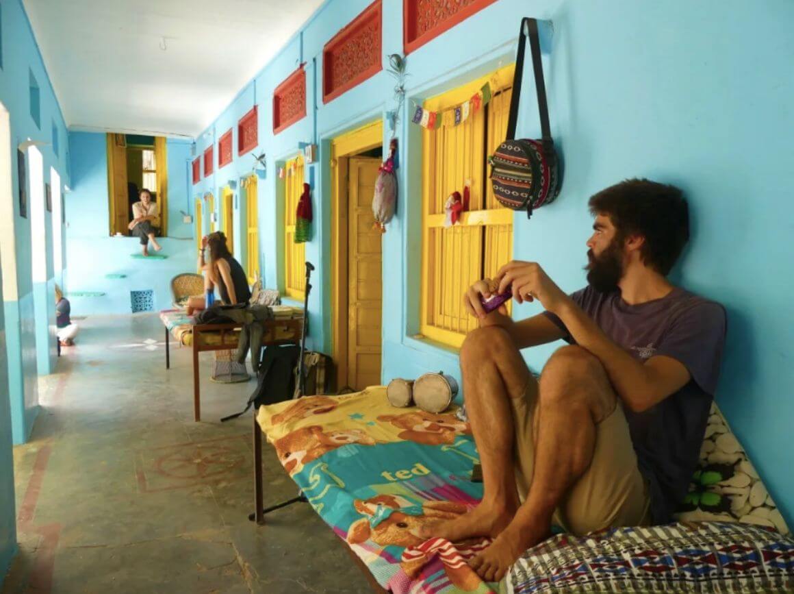 travelers sitting on charpois in a blue veranda while relaxing at one of the best hostels in the world