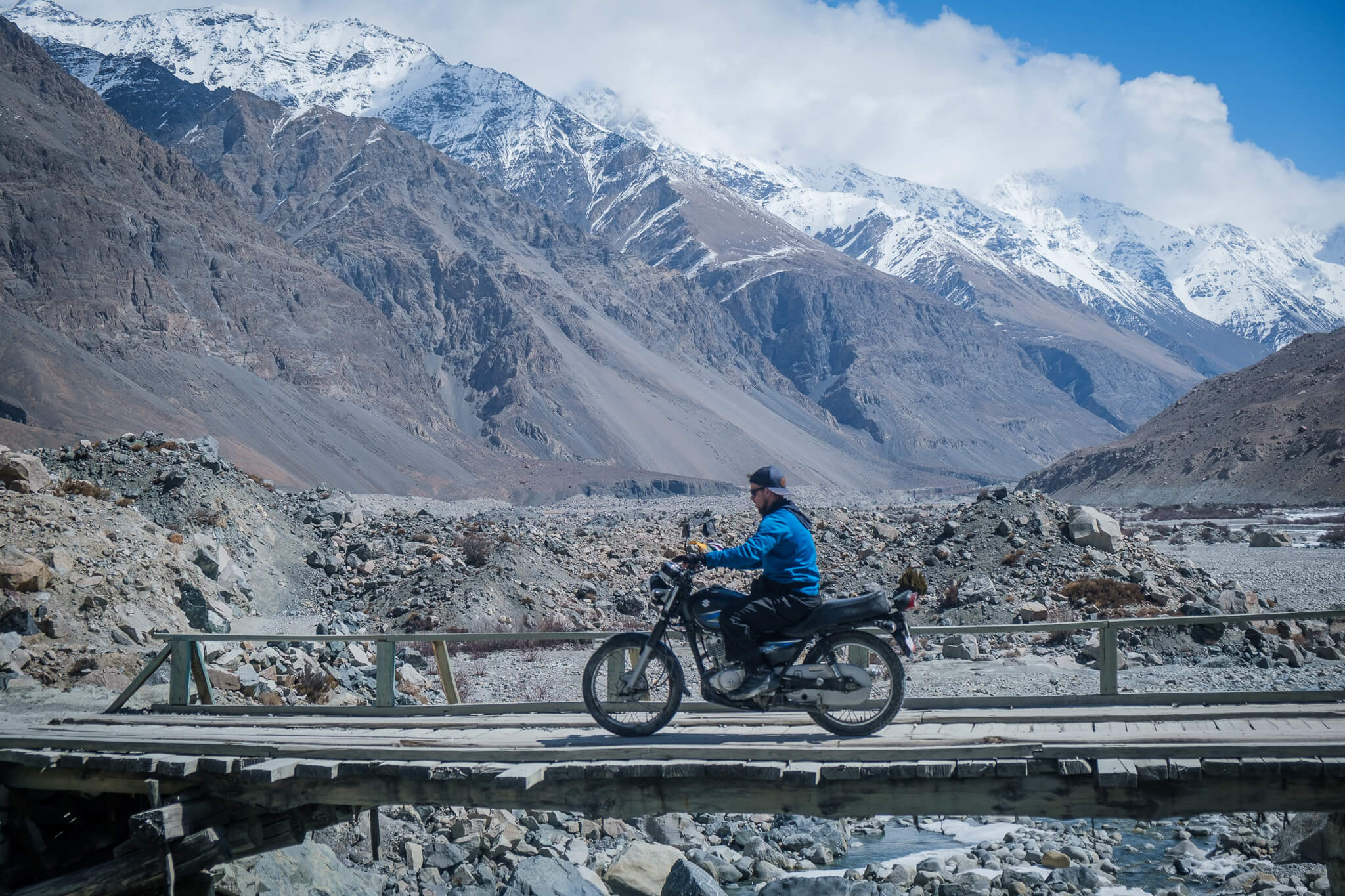 will riding a suzuki 150 motrobike over a wooden bridge in shimshal valley pakistan