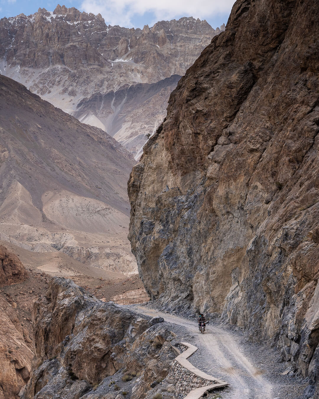 person riding a small motorbike on a dirt off road in the far north of pakistan