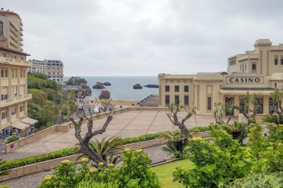 A building of the Casino Municipal de Biarritz, France with green trees and the Atlantic coastline in the background