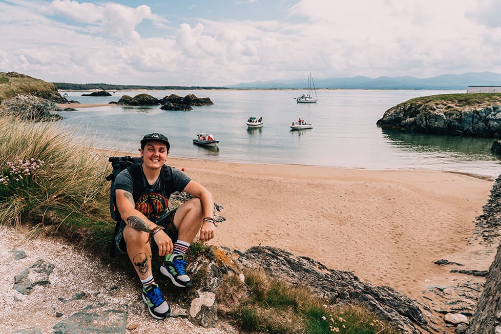 A person sat by the beach in the UK with boats in the background