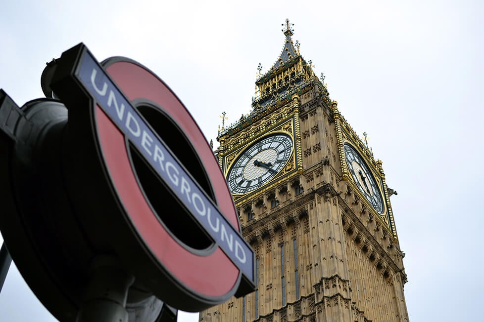 An underground sign with Big Ben in the background in London