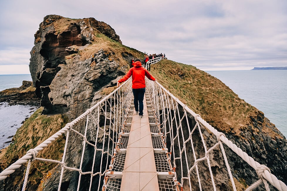 A person crossing the Carrick-a-rede rope bridge in Northern Ireland