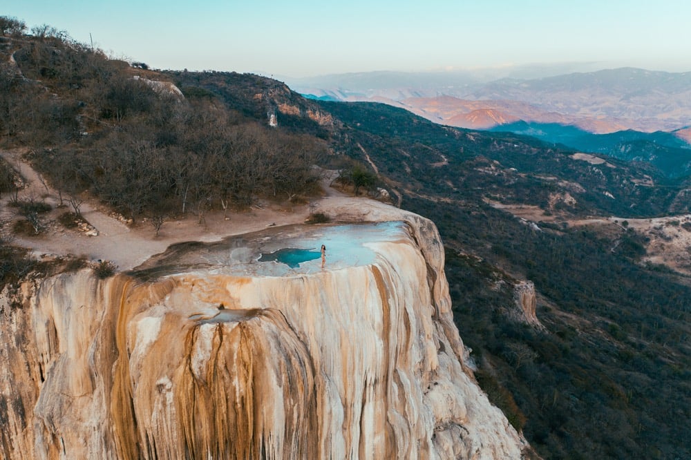 Girl on top of a white mountain with blue lakes and springs in Mexico hierve del agua