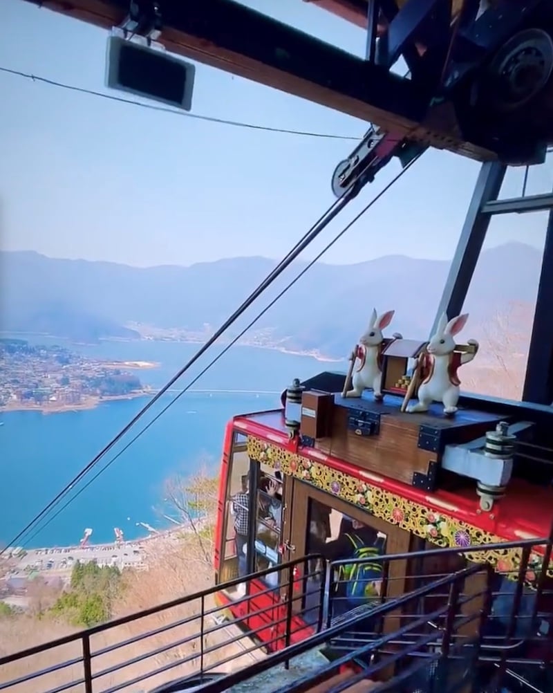 A ropeway car heads down the mountain overlooking a view od Lake Kawaguchiko.