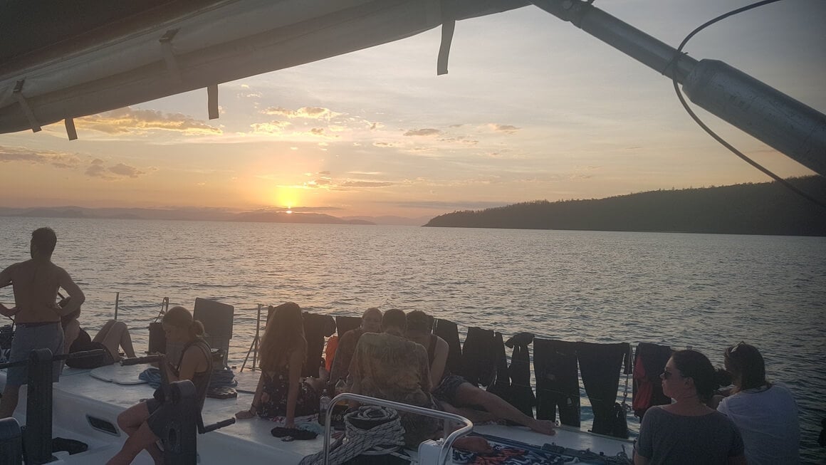 People relaxing watching the sunset on a boat tour in the Whitsunday Islands