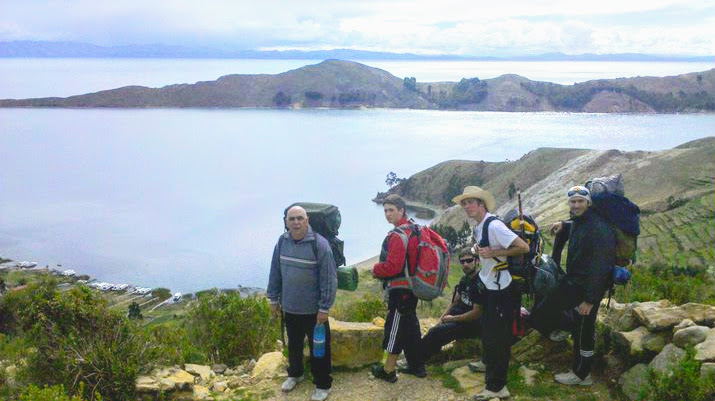 Backpackers traveling in Bolivia and the view of Lake Titicaca on the back.