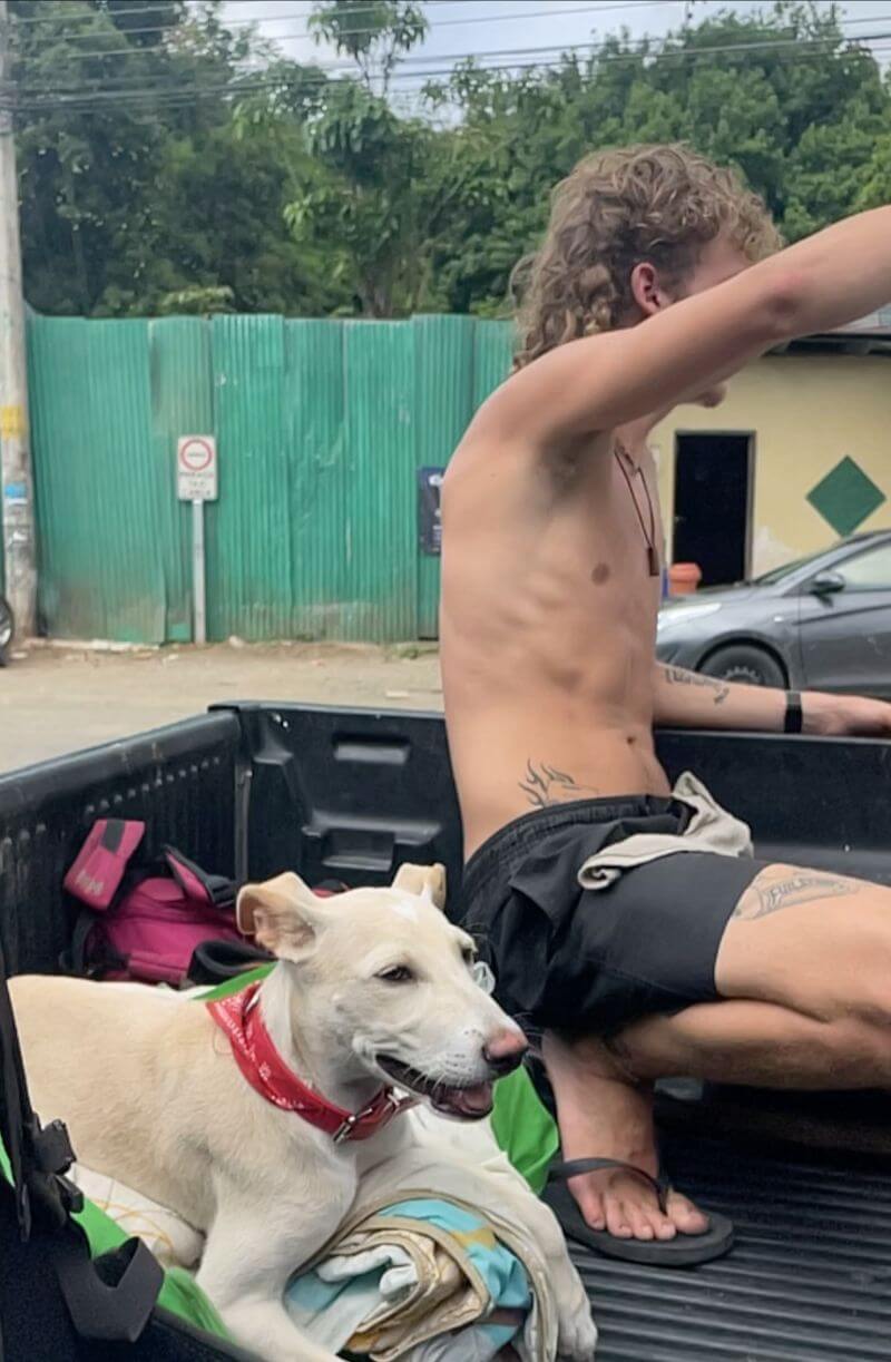 Guy in hopping into back of pickup truck with his dog in Costa Rica.
