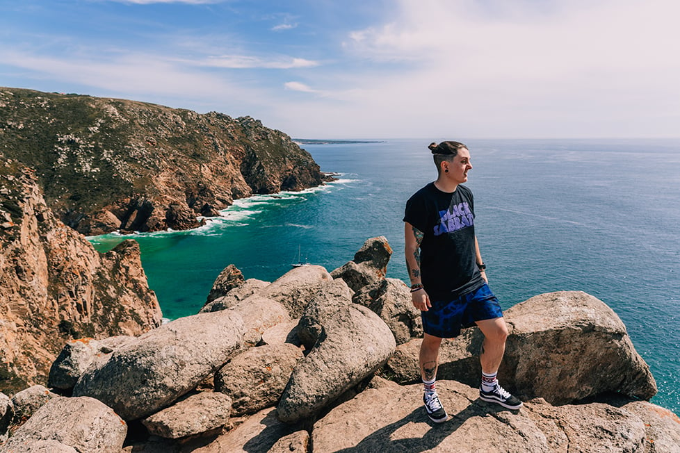 A person looking out over the coast stood on top of some cliffs