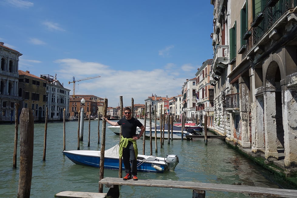 A person stands on a walk way over a main canal in Venice, Italy