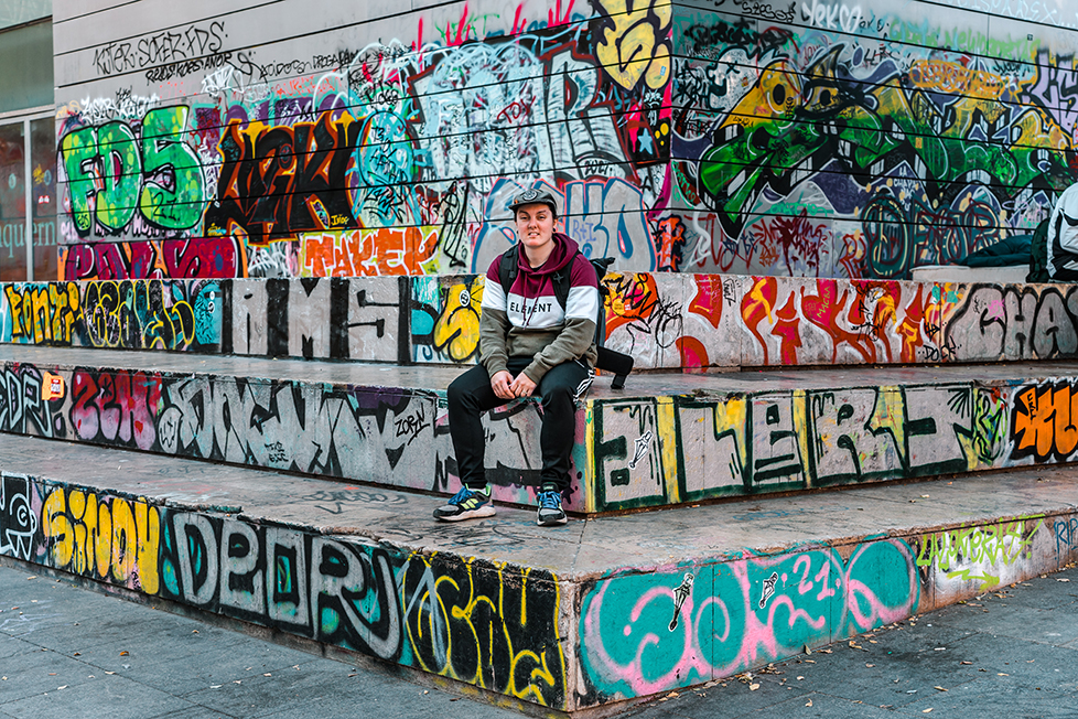 A person hanging out on some steps in Barcelona surrounded by graffiti