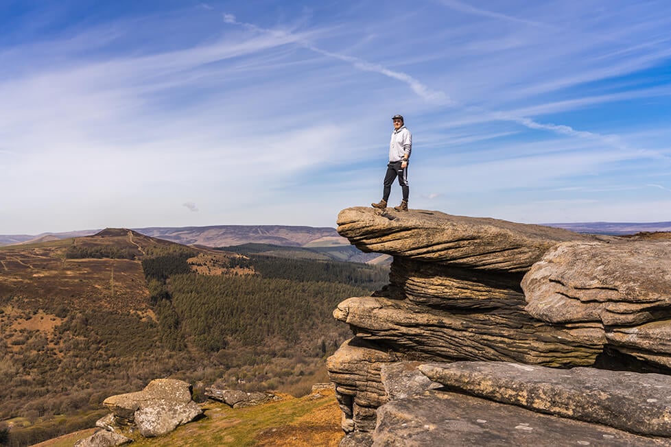 A person stood on a rocky outcrop overlooking the moors.