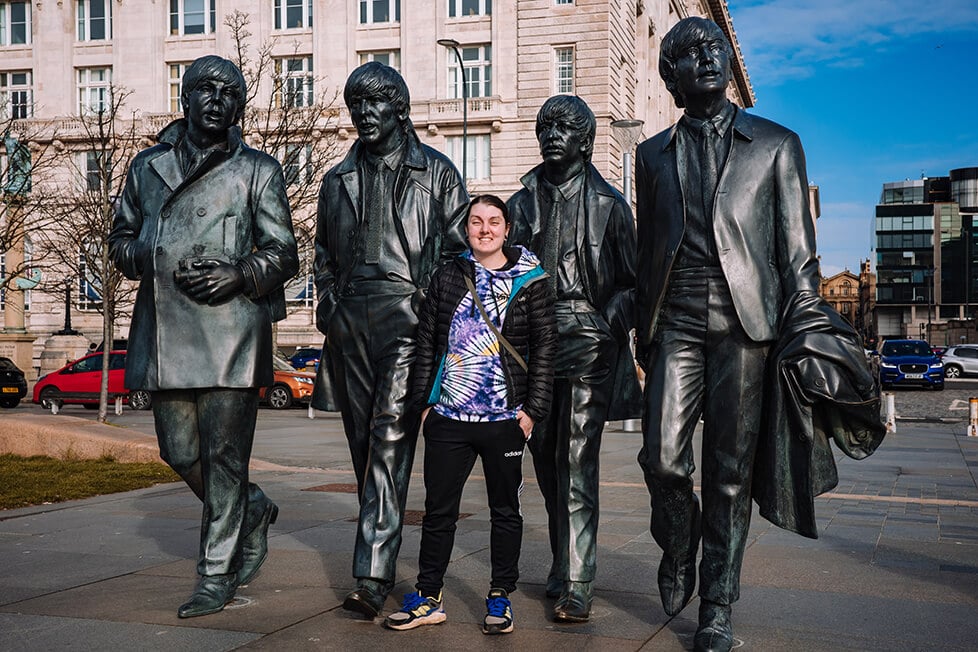 A person stood in front of a statue of The Beatles in Liverpool