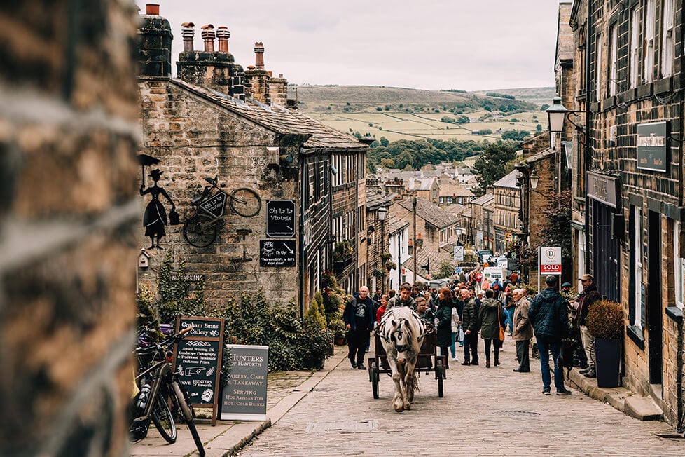 A horse and card on a cobbled street in a village in Yorkshire with the moors in the background