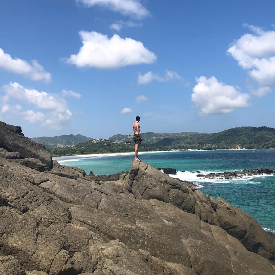 Man on rocks in Indonesia looking out to sea